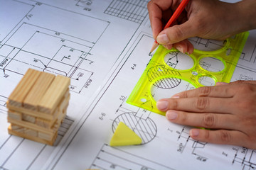 Man architect draws a plan, graph, design, geometric shapes by pencil on large sheet of paper at...