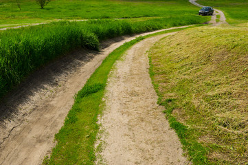 dirt road in the field and the car