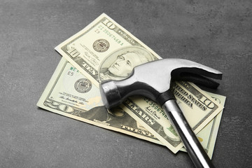 Money with hammer on grey background, close up