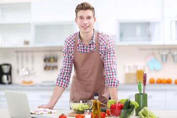 Handsome man cooking vegetable salad in kitchen