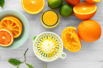 Juicy slices of oranges and juicer on white wooden table