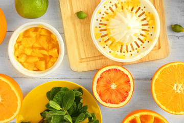 Cutting and juicing delicious oranges on white wooden table