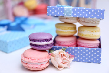 Tasty macaroons and rose in box on love word background