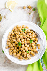 Roasted spicy chickpeas with zaatar or zatar on white bowl on wooden background. Top view