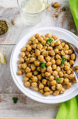 Roasted spicy chickpeas with zaatar or zatar on white bowl on wooden background. Top view