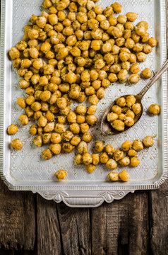 Roasted spicy chickpeas with zaatar or zatar on vintage metall try and wooden background. Top view