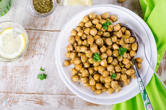 Roasted spicy chickpeas with zaatar or zatar on white bowl on wooden background. Top view