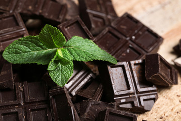 Chocolate pieces and mint on wooden background