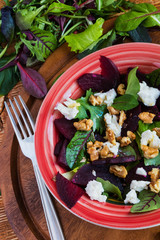 Salad: beet salad with feta cheese and walnuts on wooden background.
