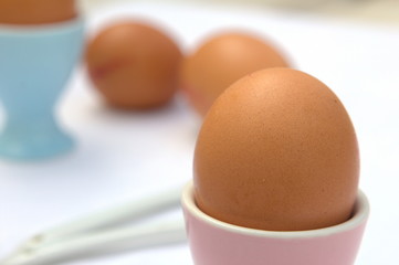 Eggs in pink and blue egg cups on a table in shallow focus