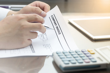 Business man review company invoice on his desk made a payment.