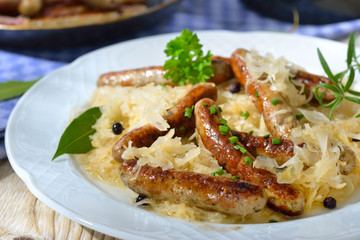 Deftige, gebratene Rostbratwürstchen auf Sauerkraut serviert - Fried Bavarian sausages from Nuremberg served on sauerkraut 