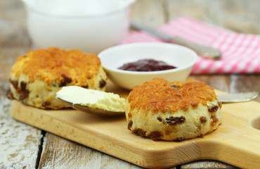 English scones with raisins on wooden board, clotted cream and jam
