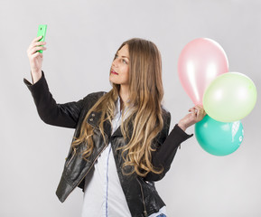 girl model in studio with balloons makes selfie