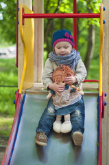 happy little girl on slide at children playground with a toy