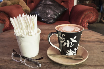 hot coffee with tissue paper coffee on wooden table coffee and sunglasses coffee near red sofa