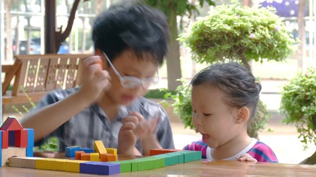 Little asian children playing with colorful construction blocks on table 