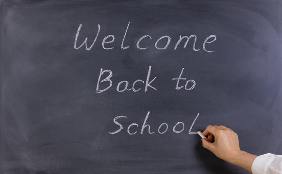 Teacher Writing Welcome Back To School On Erased Chalkboard