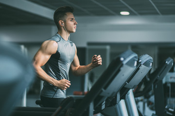 Young man in sportswear running on treadmill at gym - Powered by Adobe
