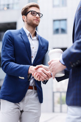 Attractive young men are greeting with handshake
