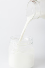 Milk pouring from a bottle in a glass isolated on a white background