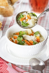 Submission chicken soup with noodles, potatoes and carrot in a white chalice on a tablecloth into a cell