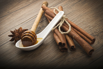 wooden honey dipper and spices on wood table