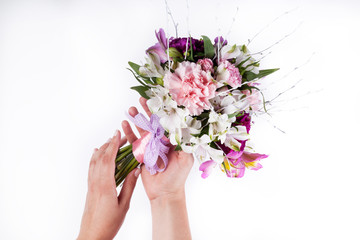 Hands holding a pastel bouquet from pink and purple gillyflowers