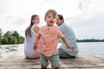 Familie sitzt auf Steg am See oder Teich