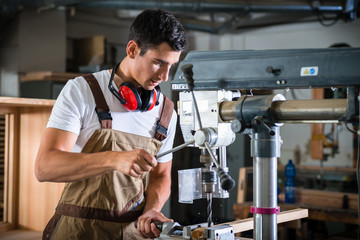 Tischler oder Schreiner arbeitet an Bohrmaschine