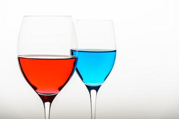 two glasses with blue colored water and wine
