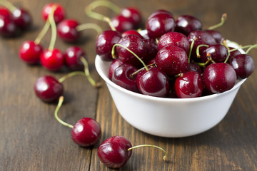 Sweet ripe cherries in white bowl on a table.