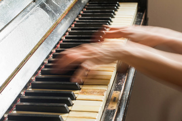 Old rusty piano, selective focus, woman's hands on keyboard, intentionally blurred motion