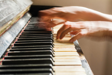 Old rusty piano, selective focus, woman's hands on keyboard, intentionally blurred motion
