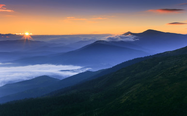 Sunrise landscape of foggy and cloudy mountain valley. 