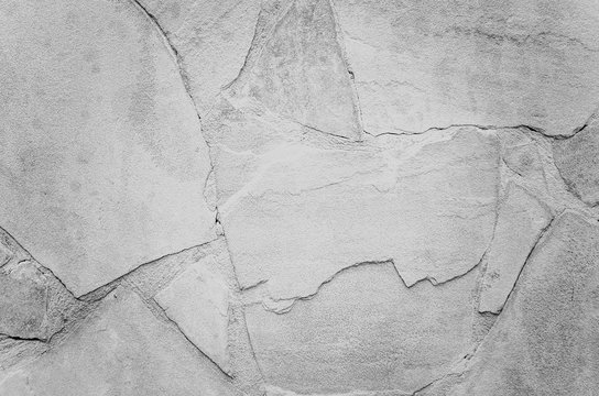 Rough stone wall with cracks of grey.