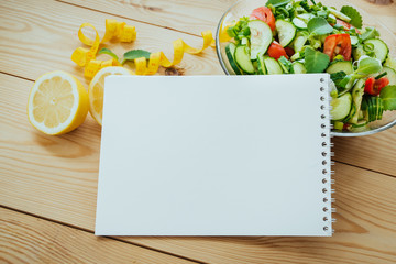 Diet plan, menu or program, tape measure and diet food of fresh vegetable salad, lemon on wood background, weight loss and detox concept, top view