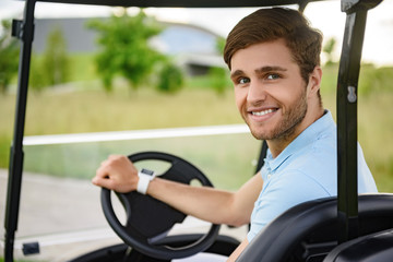 Young golfer driving golf cart