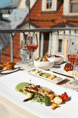 Table for two with food at rooftop restaurant, grilled fish  garnish.