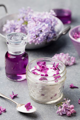 Obraz na płótnie Canvas Lilac flowers sugar and syrup, essential oil with flower blossoms in glass jar Grey stone background