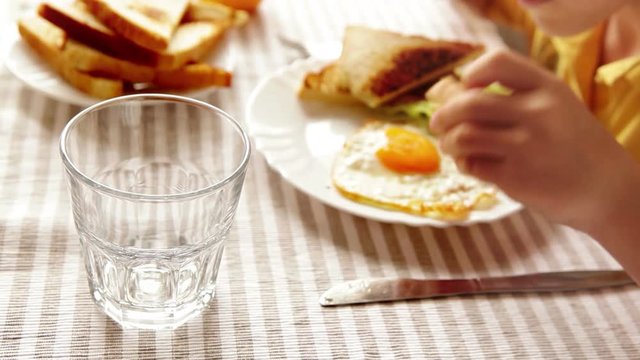 A child's having breakfast (eggs with toast and salad) and orange juice