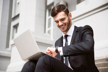 Cheerful businessman sitting on the footsteps