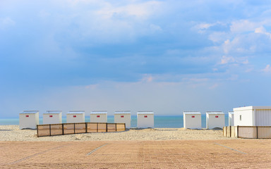 Fototapeta na wymiar Sandy beach of North Sea / Roofed beach chairs at beach of Nieuwpoort in Belgium