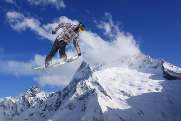 Naklejka na ściany i meble Snowboard rider jumping on mountains. Extreme freeride sport.