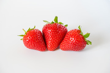 Three tasty ripe and red strawberries with leaves