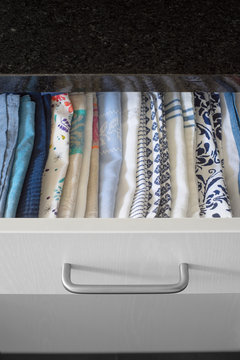 Tea towels smartly arranged in a drawer of kitchen cabinet. Selective focus.