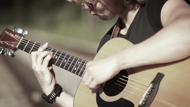 A close up portrait of a guitarist playing chords-based melody