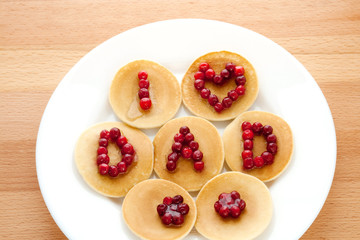 Pancakes with cranberries and syrup on a wooden background. Father's Day. Breakfast.