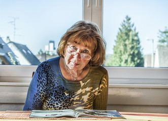 elderly attractive woman reading in a magazine
