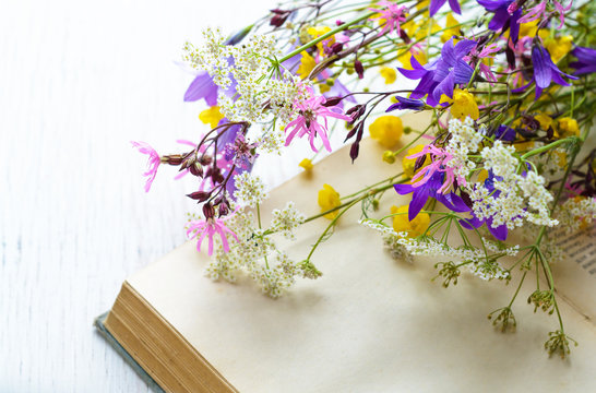 Vintage book with bouquet of meadow flowers, nostalgic vintage background